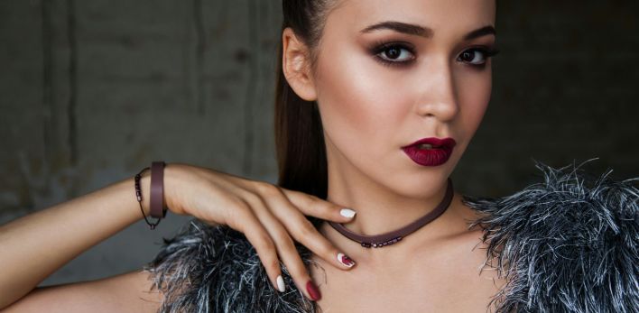 Close-up portrait of an elegant woman with bold makeup and fashionable attire, exuding confidence.
