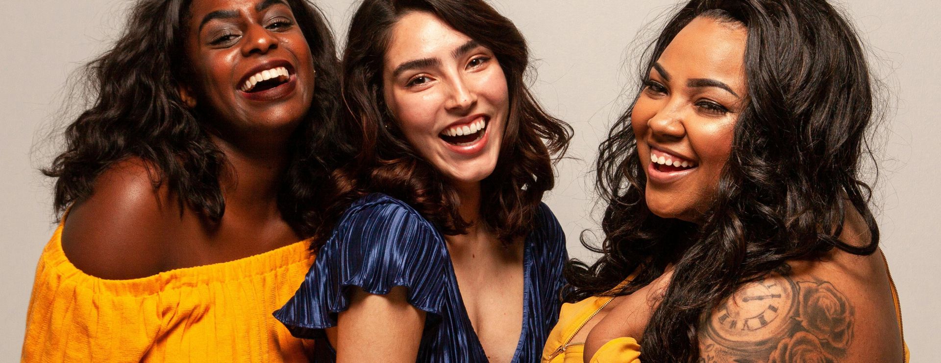 Joyful group of diverse women laughing together in bright outfits.
