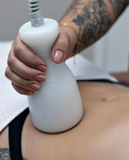 A tattooed therapist performs a body contouring procedure on a client's abdomen in Belo Horizonte.